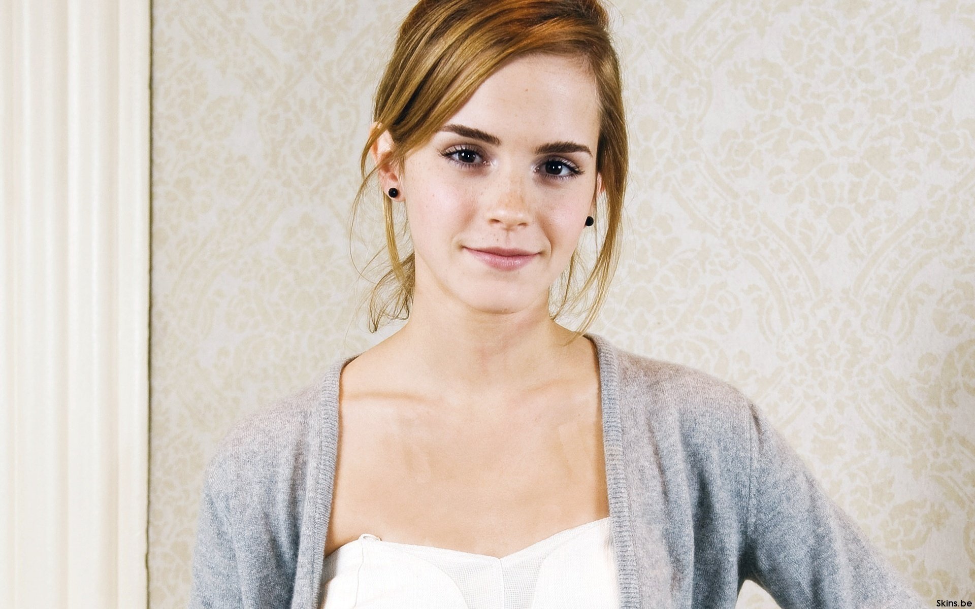 Emma Watson poses gracefully in a light cardigan against an elegant background, captured in an HD wallpaper designed for fans and admirers.