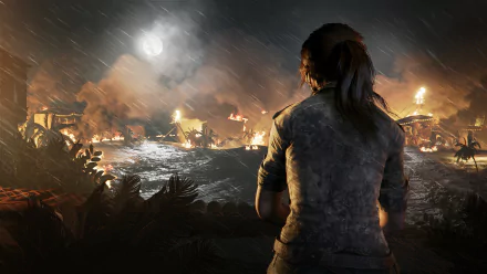 Lara Croft stands overlooking a burning village at night in this HD PC desktop wallpaper from the video game Shadow of the Tomb Raider.
