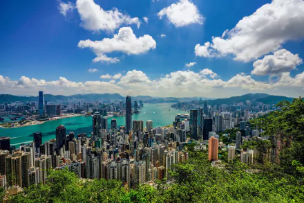 HD desktop wallpaper showing Hong Kong’s cityscape with numerous skyscrapers under a bright blue sky with scattered clouds, highlighting the man-made urban landscape in China.