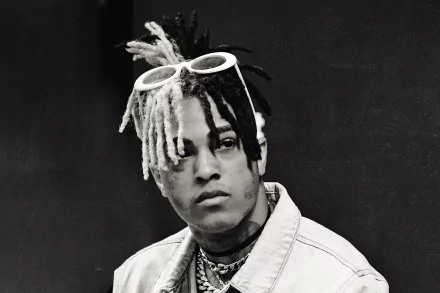 Black and white HD desktop wallpaper featuring XXXTentacion with dreadlocks and sunglasses on his head, set against a dark background.