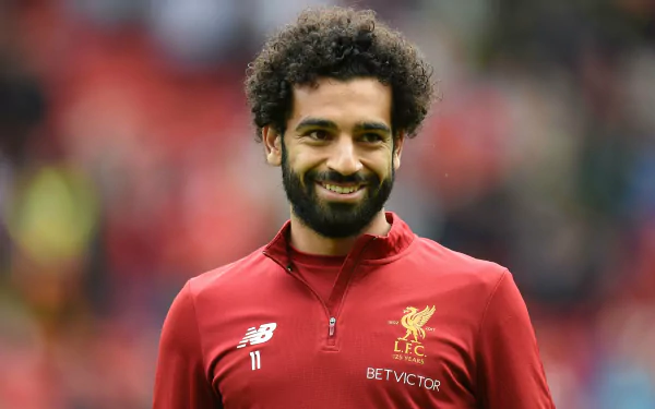 4K Ultra HD PC desktop wallpaper of an Egyptian soccer player smiling in a red Liverpool training top, sports portrait on a blurred stadium background.