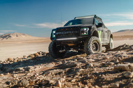 Ford F-150 Raptor parked on rocky desert terrain beneath a wide blue sky — high-detail 5K Ultra HD PC desktop wallpaper.