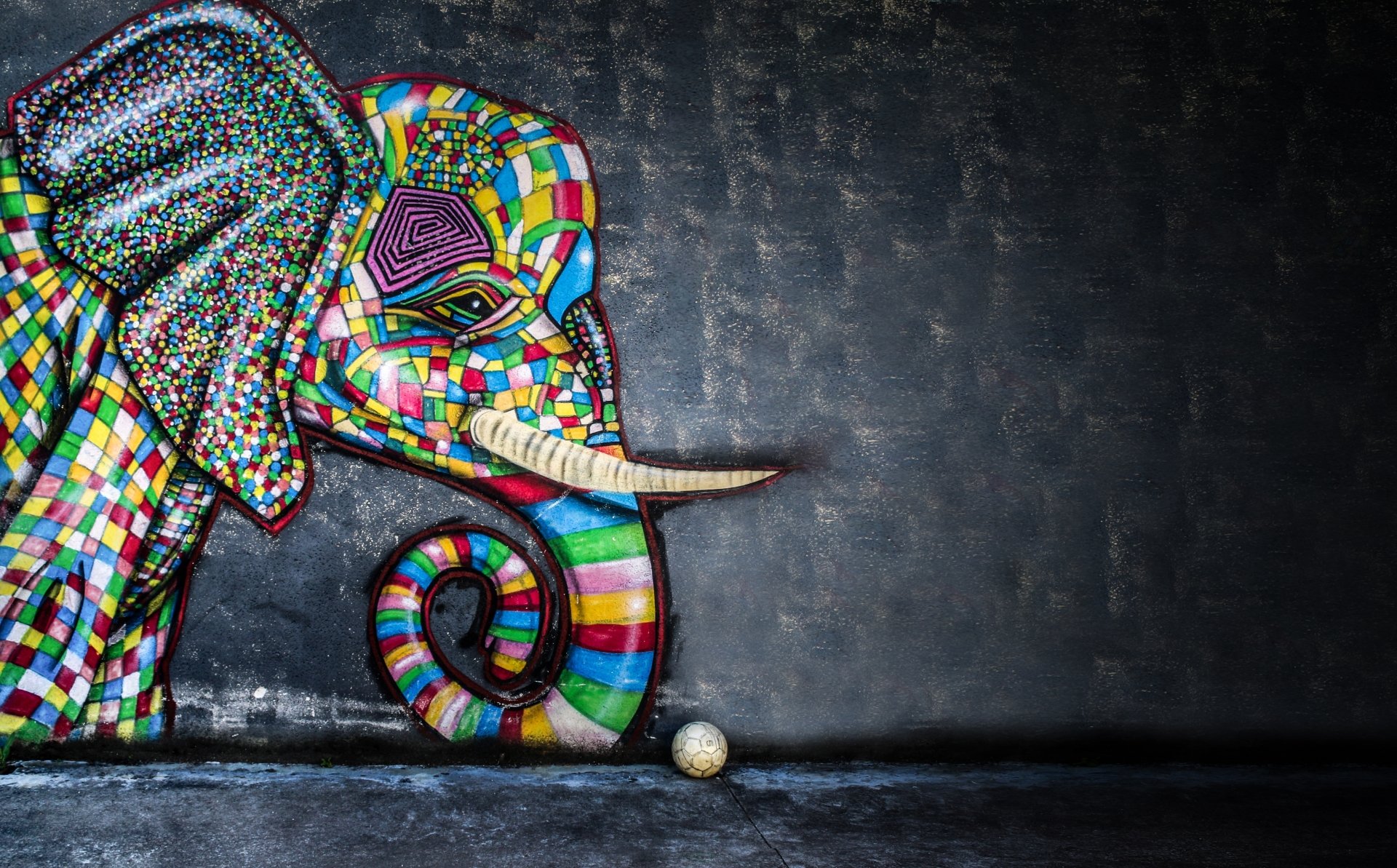 5K Ultra HD PC desktop wallpaper: artistic graffiti elephant in multicolored tiles curls its trunk toward a soccer ball against a dark textured wall.