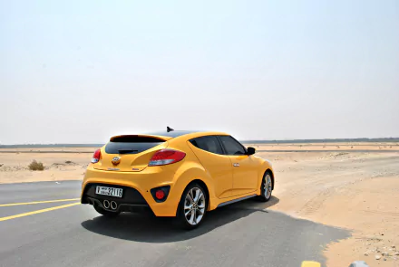 Yellow Hyundai Veloster car on a desert road, rear three-quarter view — 4K Ultra HD PC desktop wallpaper of the sporty hatchback vehicle.