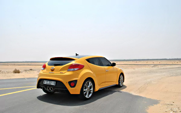 Yellow Hyundai Veloster car on a desert road, rear three-quarter view — 4K Ultra HD PC desktop wallpaper of the sporty hatchback vehicle.