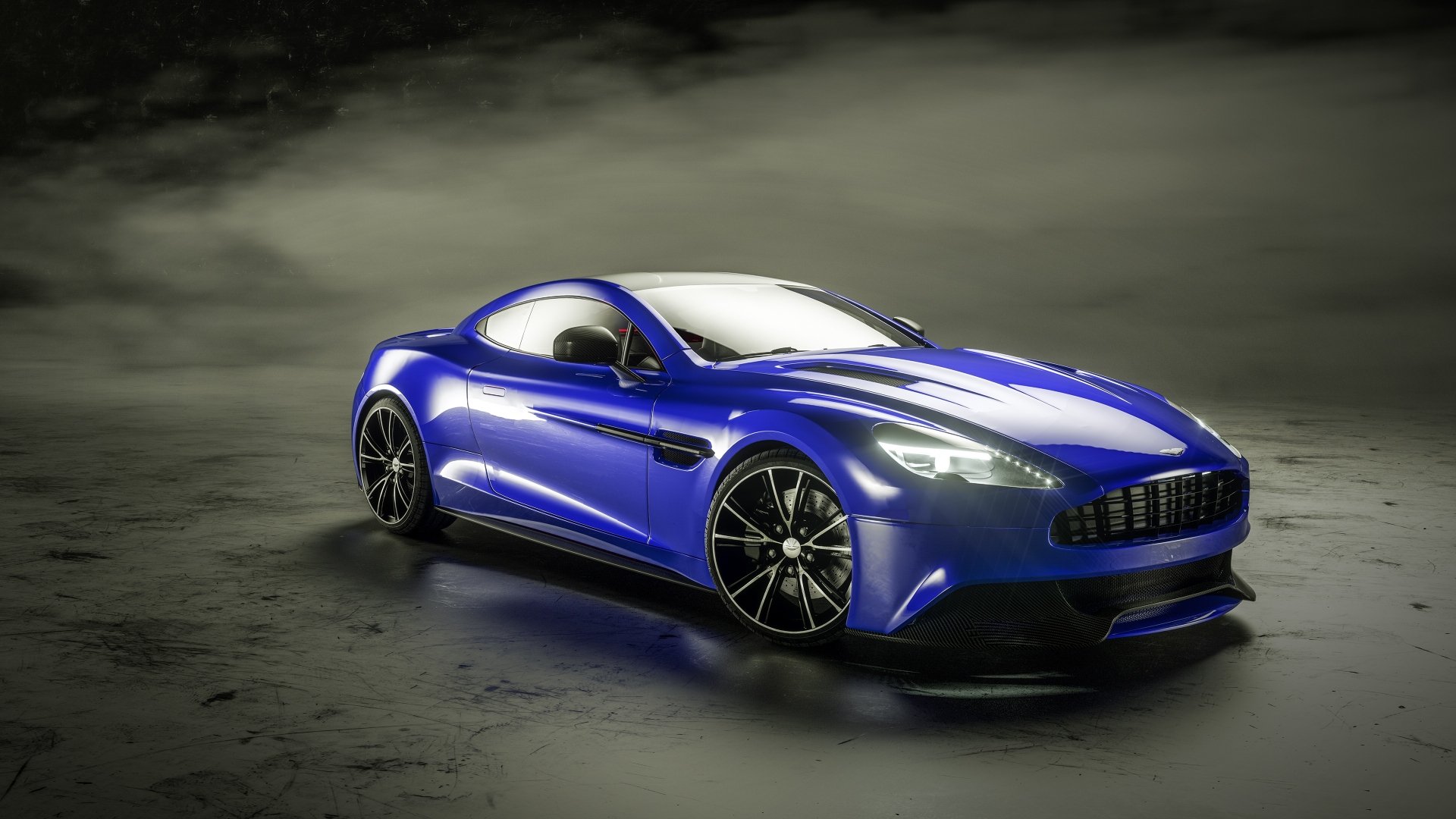 Blue Aston Martin Vanquish grand tourer supercar on reflective wet pavement, high-detail 4K Ultra HD PC desktop wallpaper background.