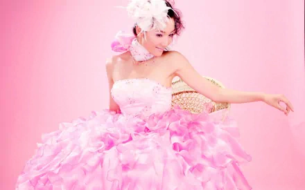 A joyful bride in a stunning pink gown adorned with ruffles, set against a soft pink background, making for a vibrant HD desktop wallpaper.