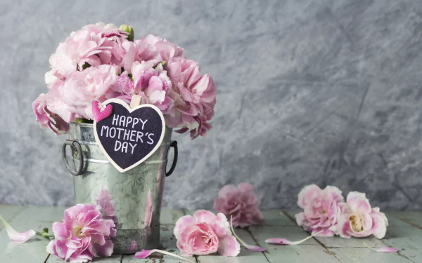 A 4K Ultra HD still life of pink flowers arranged in a metal bucket with a Happy Mother's Day tag, set against a gray textured background.