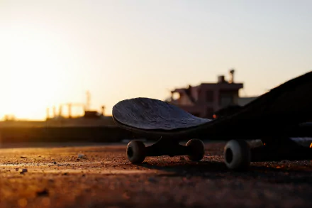 Skateboard resting on pavement at sunset, capturing the essence of skateboarding and sports in a stunning 4K Ultra HD PC desktop wallpaper and background.