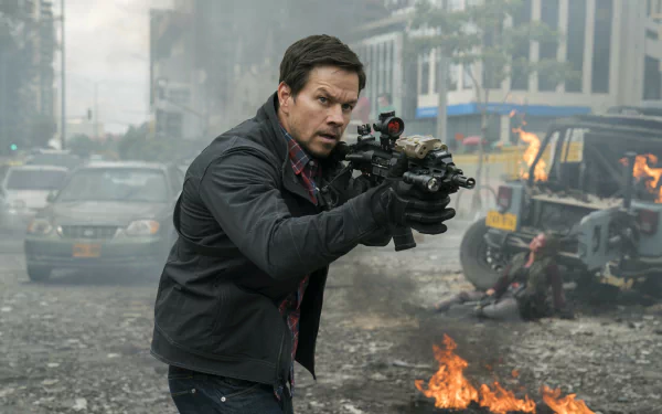 HD desktop wallpaper featuring Mark Wahlberg aiming a rifle in an intense scene from the movie Mile 22, set in a fiery, chaotic urban environment.