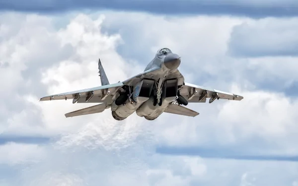 Front view of a Mikoyan MiG-29 jet fighter warplane in flight against a cloudy sky — 2K Quad HD PC desktop wallpaper background.
