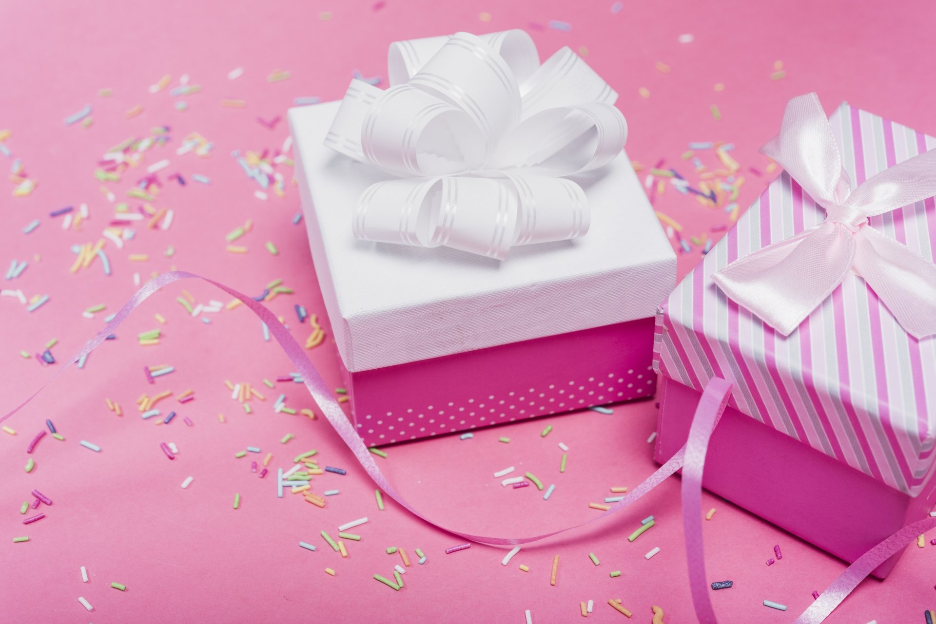 5K Ultra HD PC desktop wallpaper showing two pink-and-white wrapped gifts with bows, ribbons and scattered confetti on a pink background — celebration, Misc, gift