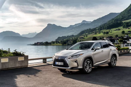 Silver Lexus RX SUV parked by a scenic lakeside road with mountains in the background, captured in high-resolution 4K Ultra HD.