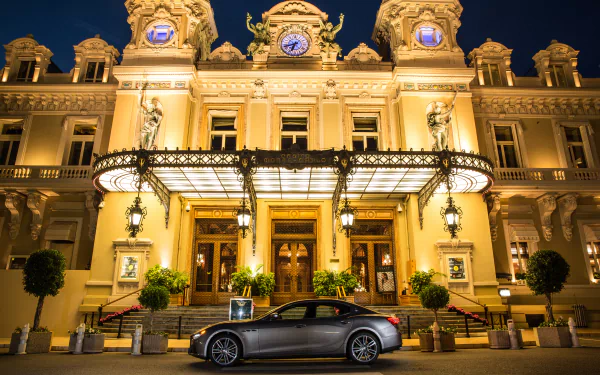 Silver Maserati Ghibli grand tourer parked in front of an ornate, illuminated historic building at night, captured in 4K Ultra HD for a PC desktop wallpaper.