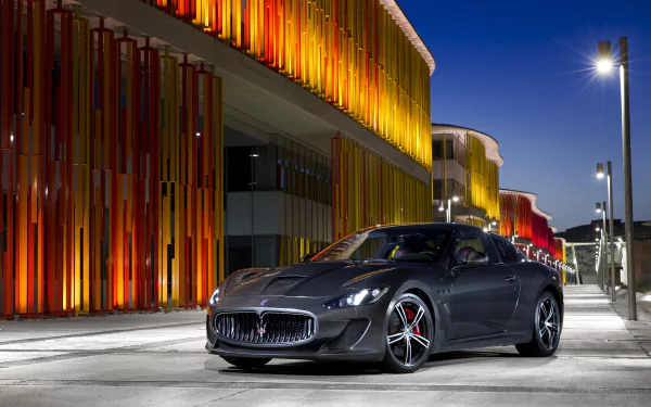 Silver Maserati GranTurismo supercar grand tourer car parked at night by an illuminated modern building — 4K Ultra HD PC desktop wallpaper