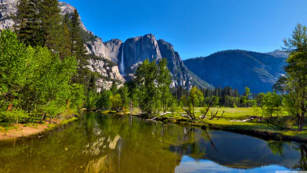 4K Ultra HD wallpaper of Yosemite National Park valley showcasing lush greenery, reflective river, and towering granite cliffs beneath a clear blue sky.