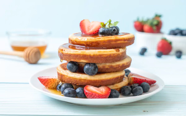 Stack of pancakes topped with fresh blueberries, strawberries, and honey, set in a bright breakfast still life, captured in 8K Ultra HD.