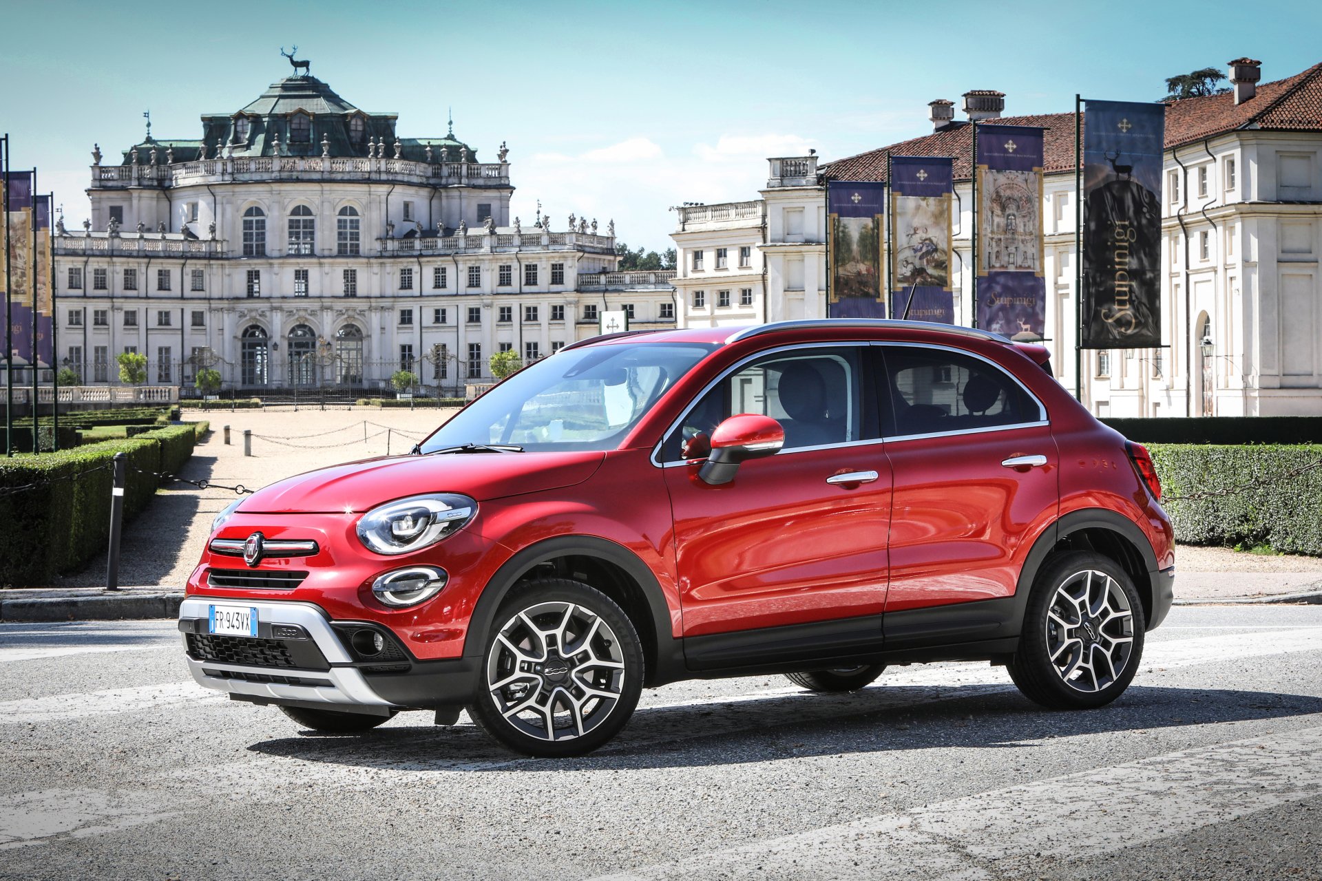 Red Fiat 500X SUV parked before an ornate European palace, 4K Ultra HD PC desktop wallpaper/background showcasing the Fiat car and vehicle in an urban plaza.
