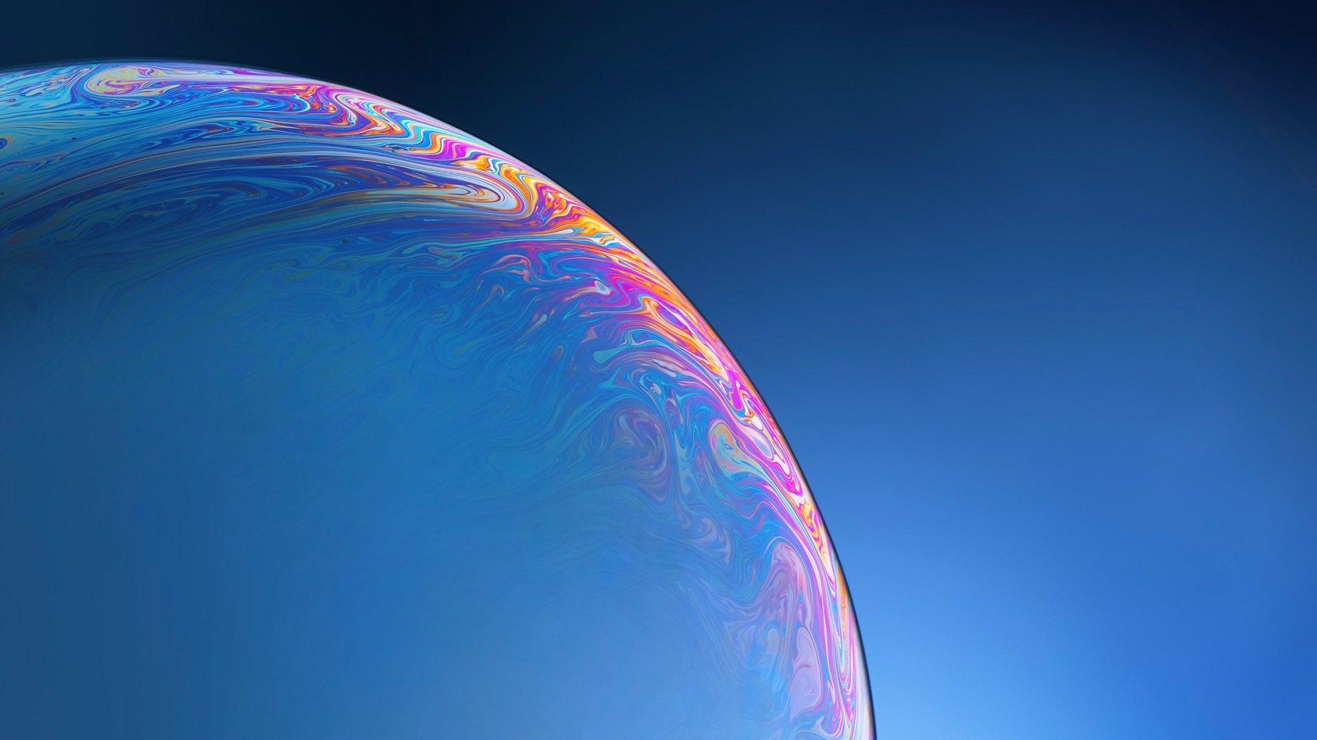 HD PC desktop wallpaper featuring an abstract close-up of a bubble with vibrant, swirling colors against a smooth blue background.