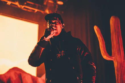 HD desktop wallpaper featuring a performance by a hip-hop artist, with warm stage lighting and a vibrant desert backdrop.