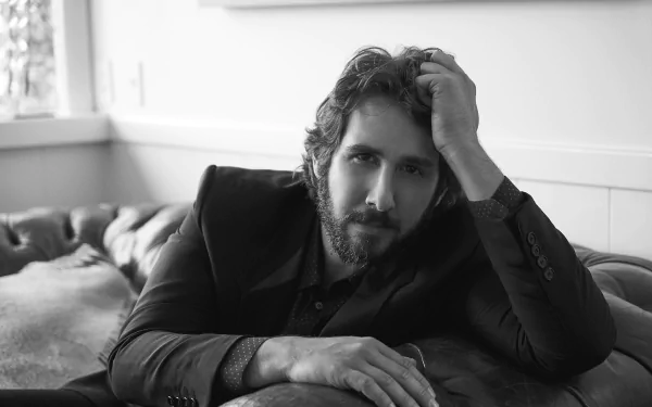 Black and white HD desktop wallpaper featuring a pensive man sitting on a couch, hand in hair, with a thoughtful expression.