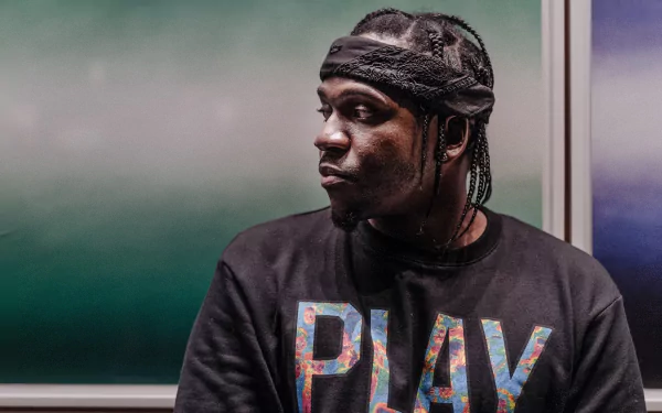 HD desktop wallpaper featuring a pensive individual in a black PLAY sweater and headband, set against a muted green background.