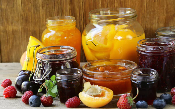 A vibrant 4K Ultra HD still life of assorted fruit jams in glass jars, surrounded by fresh berries and sliced fruit, set against a rustic wooden background.
