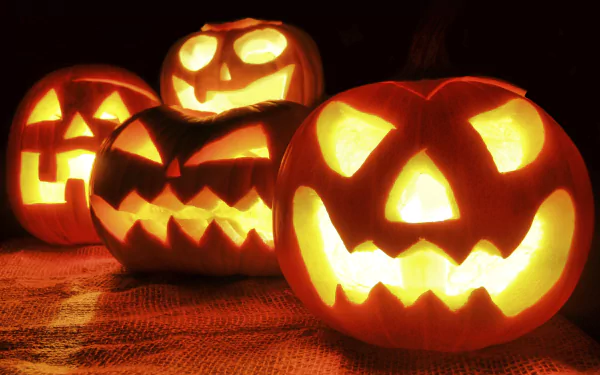 HD Halloween desktop wallpaper featuring a row of glowing jack-o'-lanterns with carved faces glowing warmly in the dark holiday setting.