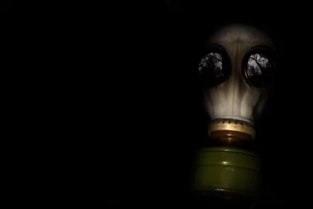 A dark and atmospheric HD desktop wallpaper featuring a gas mask illuminated by faint light, creating an eerie and mysterious ambiance.