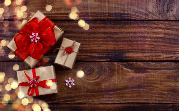 4K Ultra HD PC desktop wallpaper and background: three wrapped gifts with red bows on a rustic wooden table, warm bokeh lights scattered around.