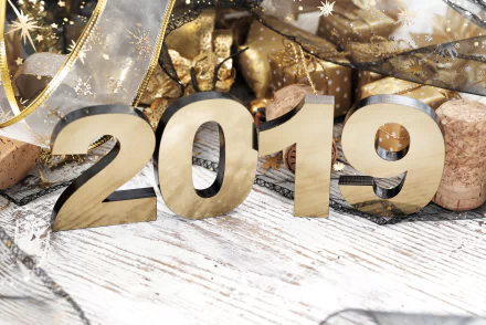 Golden 2019 numerals on a white wood table surrounded by gold ribbons, star sparkles and champagne corks — holiday New Year 2019 5K Ultra HD PC desktop wallpaper/background.