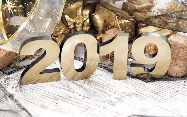 Golden 2019 numerals on a white wood table surrounded by gold ribbons, star sparkles and champagne corks — holiday New Year 2019 5K Ultra HD PC desktop wallpaper/background.