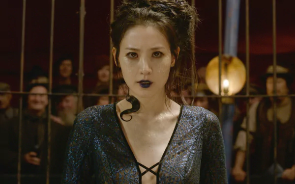 HD wallpaper of Claudia Kim from Fantastic Beasts: The Crimes of Grindelwald, featuring her in character behind bars with a snake.