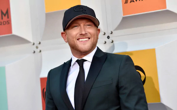 HD desktop wallpaper featuring Cole Swindell in a suit and cap, smiling at an awards show.