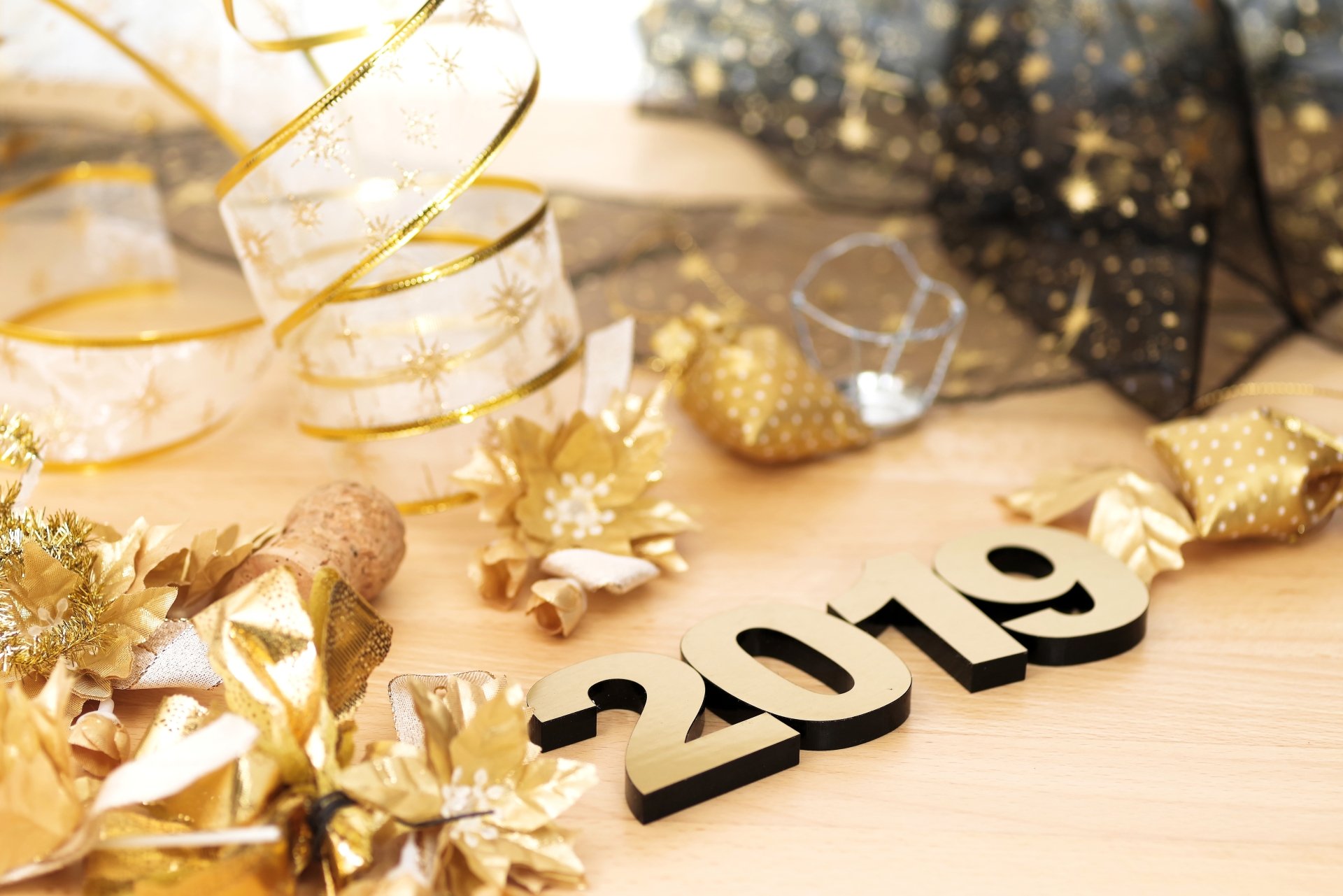 Holiday-themed 8K Ultra HD PC desktop wallpaper featuring New Year 2019 decorations with gold ribbons, ornaments, and festive elements on a light wooden surface.