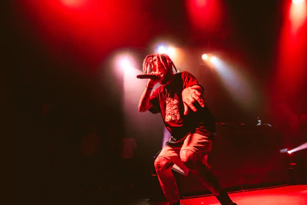 HD wallpaper of a performer on stage with dramatic red stage lighting, creating a dynamic desktop background.