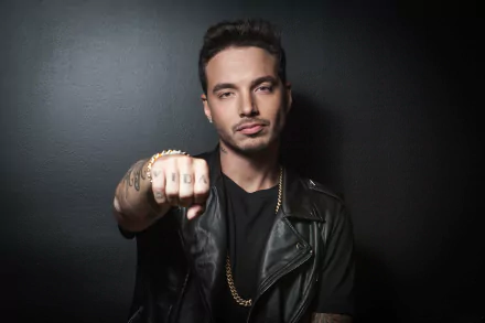 HD desktop wallpaper of a man with tattoos and a leather jacket, posing confidently against a dark background.