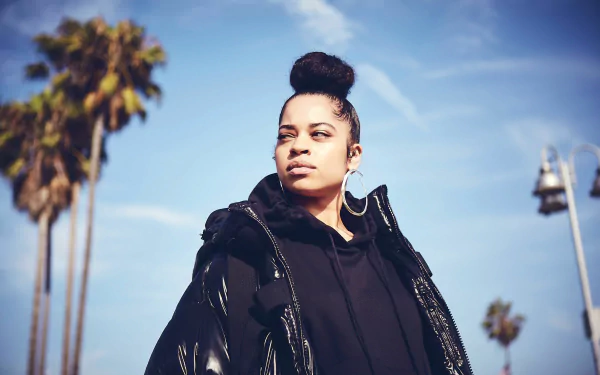 HD desktop wallpaper featuring Ella Mai in a stylish black outfit with a palm tree-lined background.