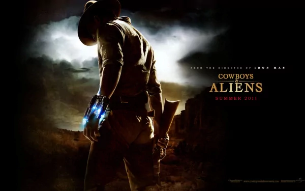 HD PC desktop wallpaper: lone cowboy seen from behind, glowing alien gauntlet on his hand, pistol holstered, stormy western skyline and 'Cowboys & Aliens' movie title.