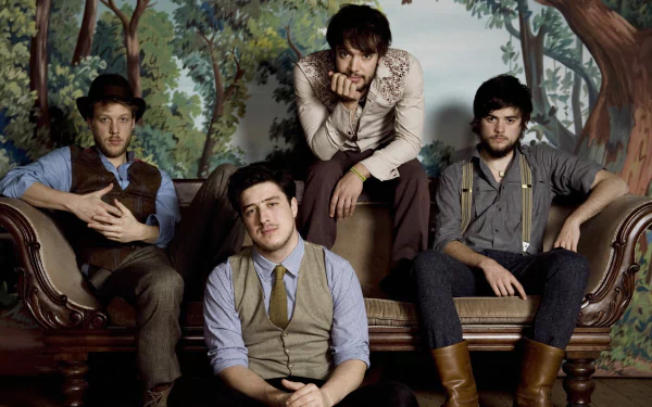 A stylish HD wallpaper featuring Mumford & Sons, showcasing the band members posed comfortably on a vintage sofa against a nature-themed backdrop.