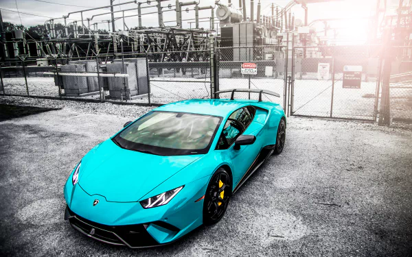 Turquoise Lamborghini Huracan Performante sports vehicle parked in an industrial lot with chain-link fence and sun flare — 5K Ultra HD PC desktop wallpaper and background.