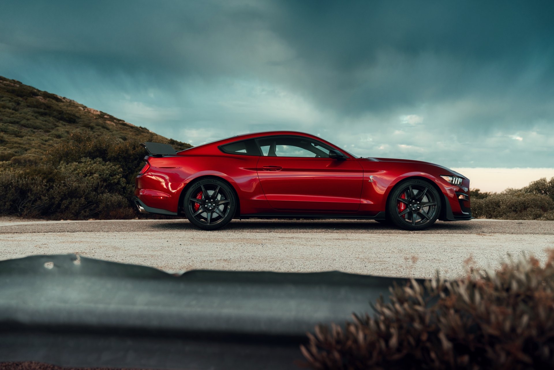 Red Ford Mustang Shelby GT500 muscle car parked on a coastal road, side profile; 8K Ultra HD PC desktop wallpaper background.