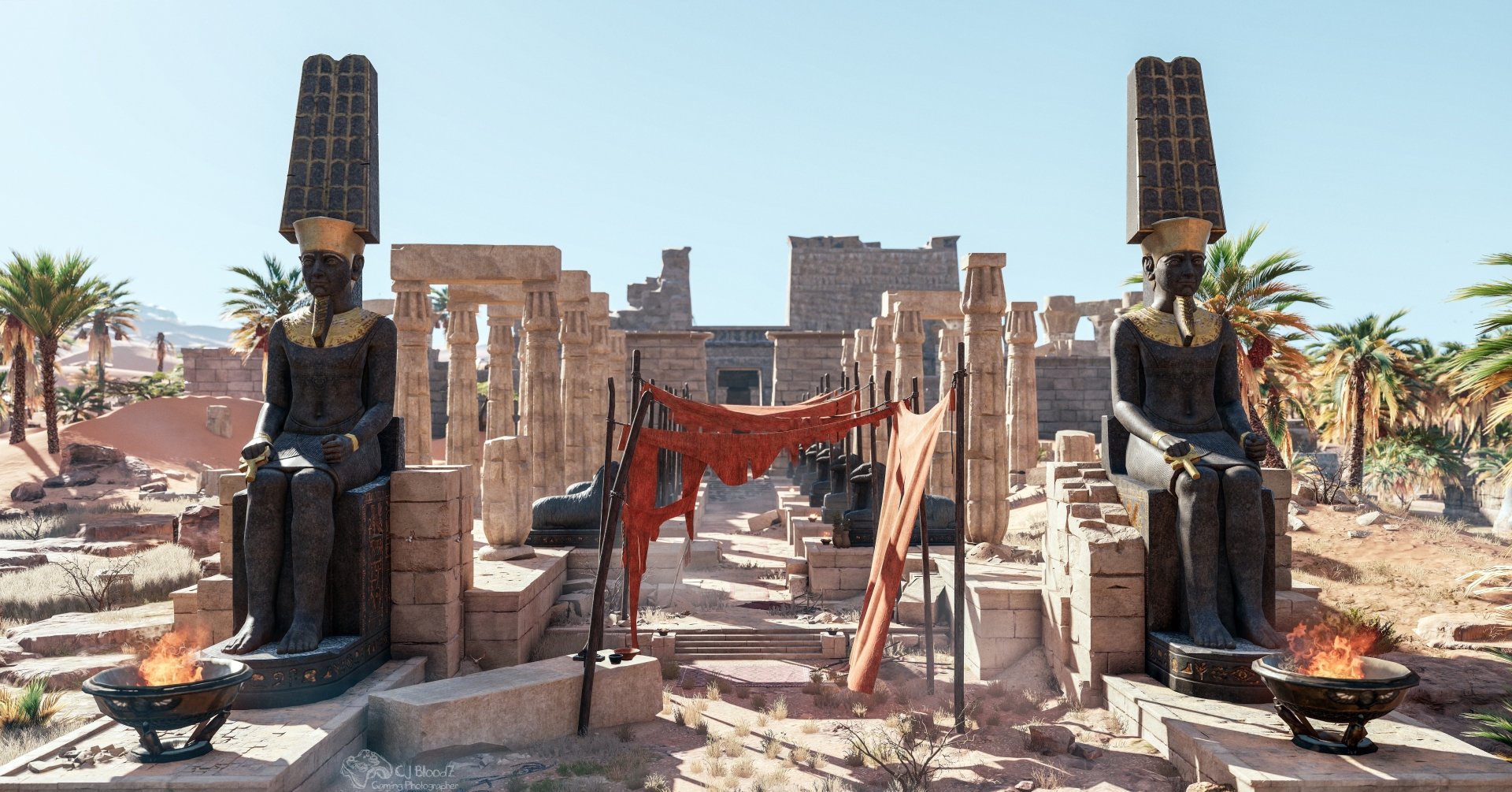 Assassin's Creed Origins (video game) 5K Ultra HD PC wallpaper: sunlit ancient Egyptian temple ruins with two seated colossal statues flanking a cloth-draped central entrance, palms and blue sky.