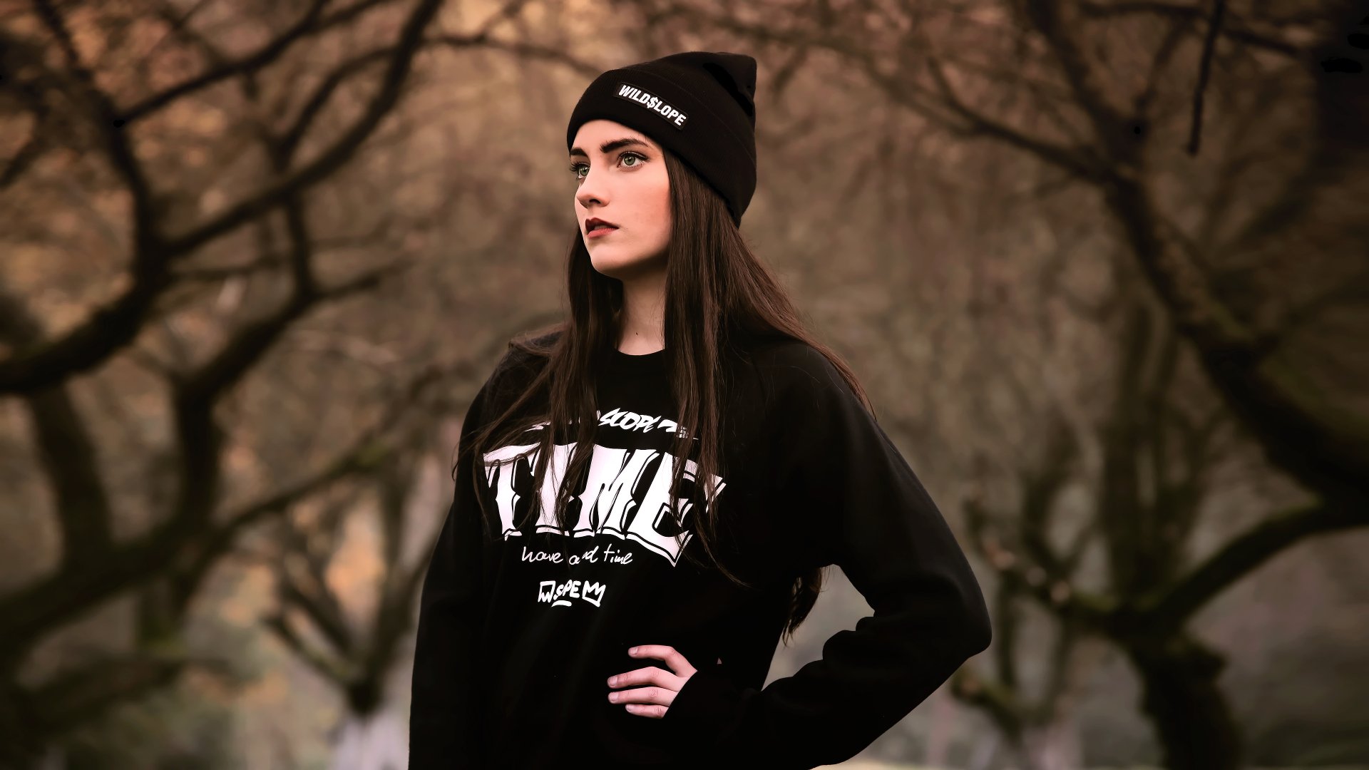 Portrait of a woman with black hair, green eyes, and lipstick, wearing a hat and black sweatshirt, captured with depth of field in a 4K Ultra HD desktop wallpaper.