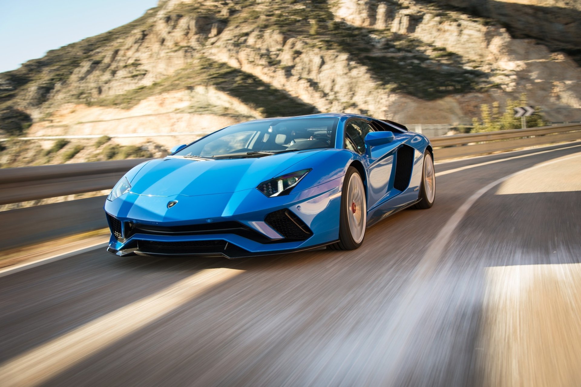 Blue Lamborghini Aventador S supercar racing along a coastal mountain road, HD PC desktop wallpaper showcasing a sleek Lamborghini sports vehicle.