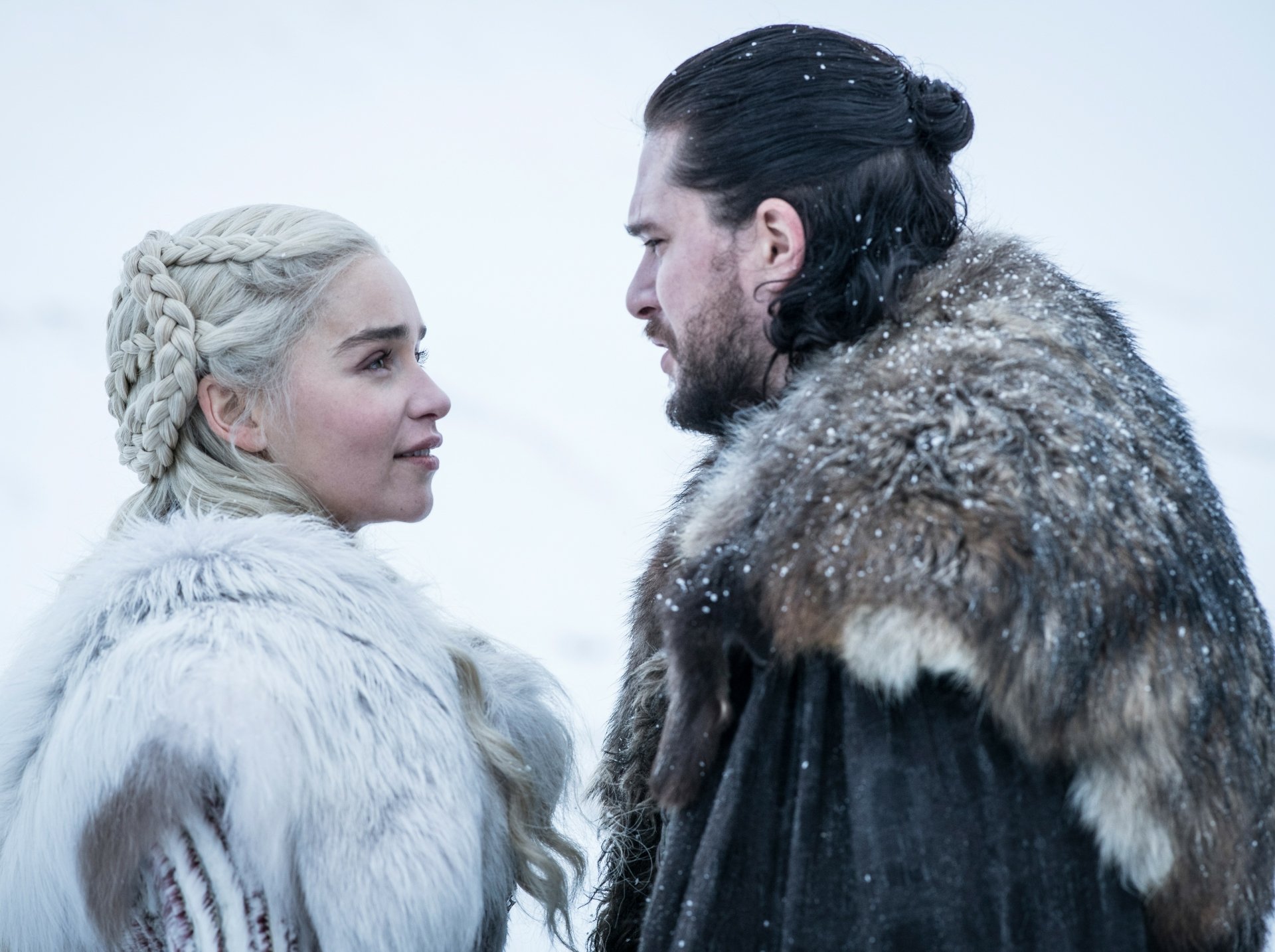 4K Ultra HD Game of Thrones wallpaper featuring Emilia Clarke as Daenerys Targaryen and Kit Harington as Jon Snow in snowy white and fur cloaks.