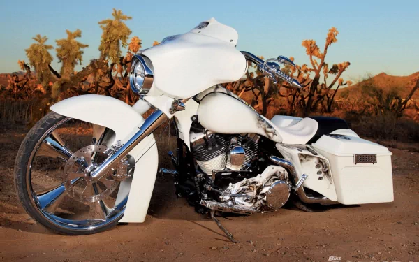 White Harley-Davidson Street Glide motorcycle with chrome accents and oversized front wheel parked in a desert at sunset — HD PC desktop wallpaper background.