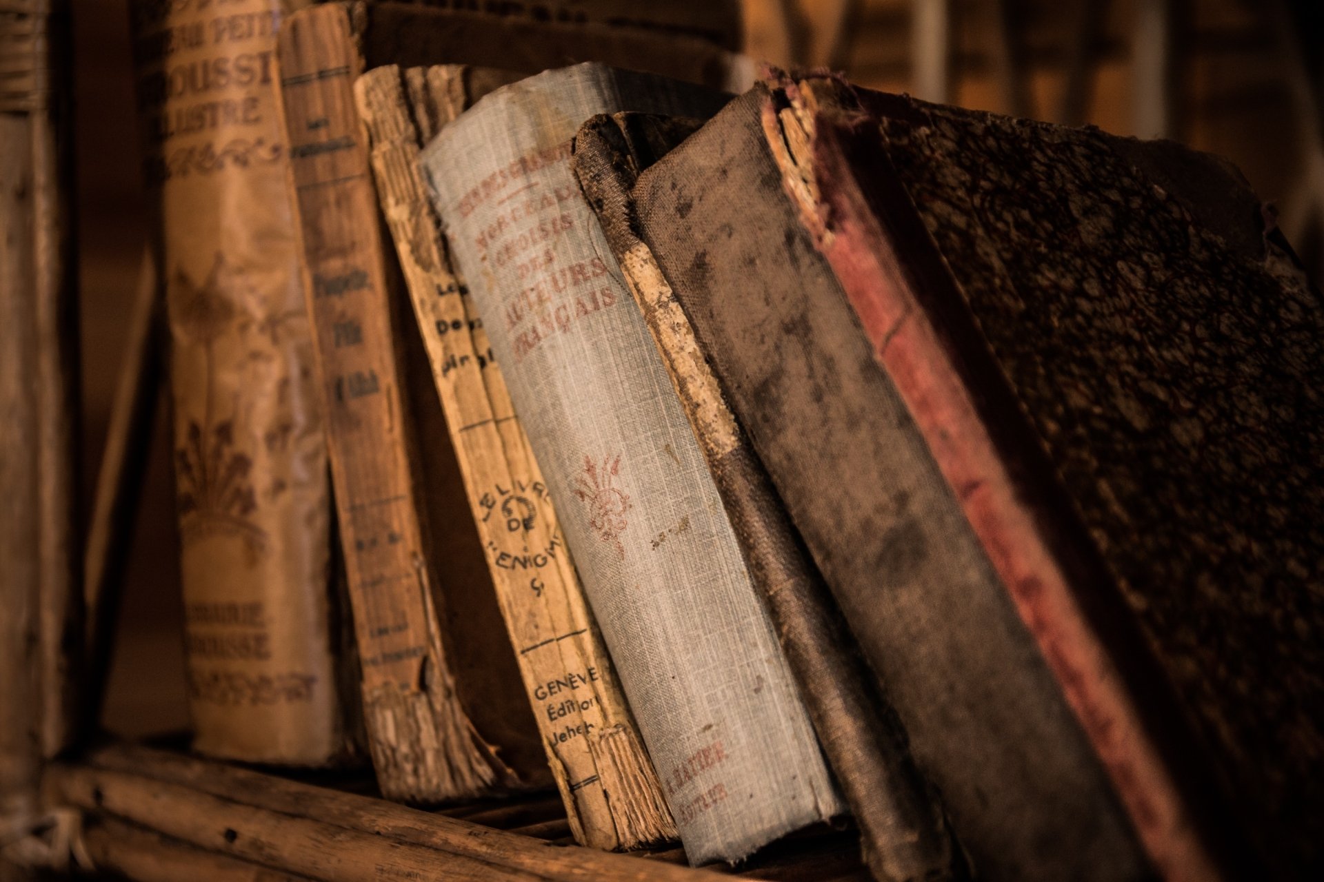 HD desktop wallpaper featuring a close-up of old, man-made vintage book covers with worn textures and faded text on a rustic shelf.