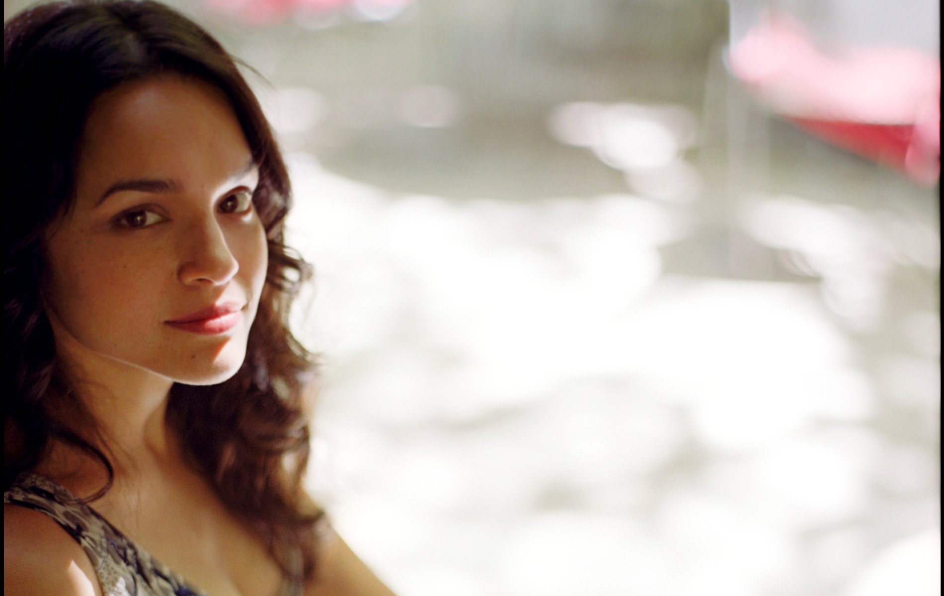 HD PC desktop wallpaper of a softly lit female singer with a warm smile and loose curls, blurred bokeh background evoking a mellow jazz music mood.