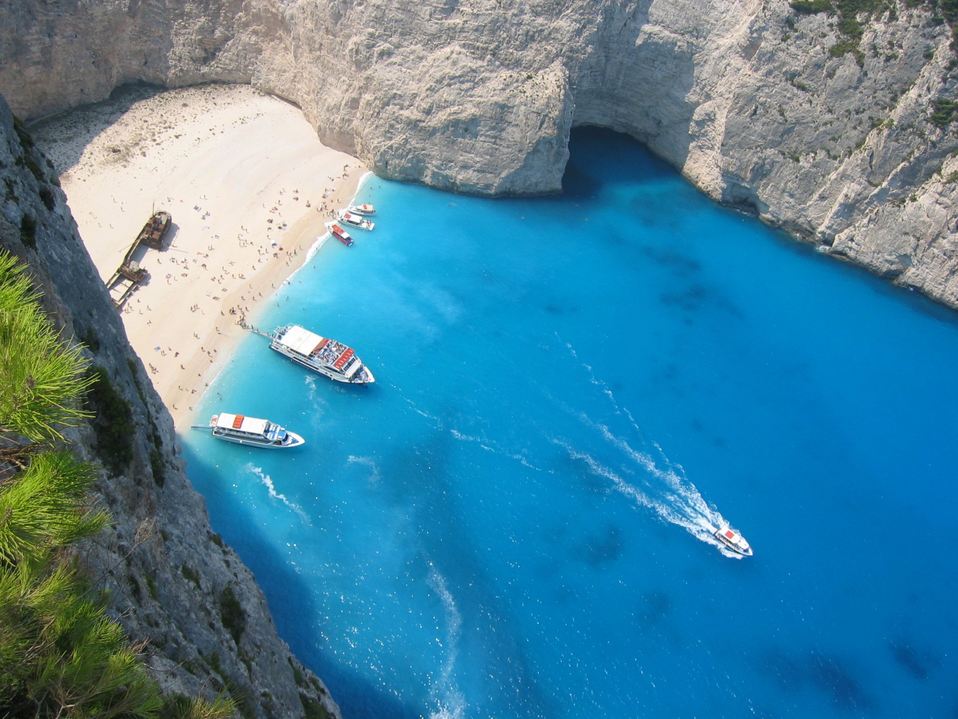 HD PC desktop wallpaper featuring a stunning nature scene with turquoise waters, boats, and a sandy beach surrounded by towering cliffs.